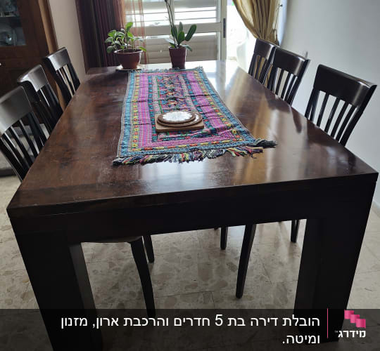 שולחן עץ עם מפה צבעונית ושני עציצים